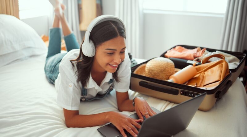 Computer travel and woman packing for a vacation with headphones typing a holiday blog. Adventure,