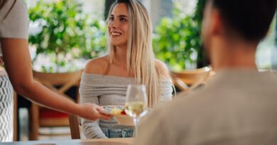 Smiling woman receiving food from waitress in restaurant