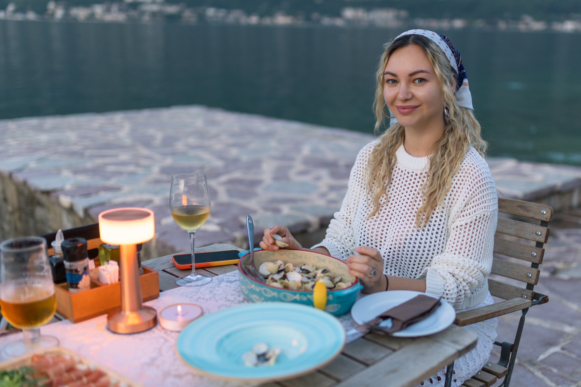 A woman eats mussels, a traditional Montenegrin dish, while sitting on the terrace of a restaurant