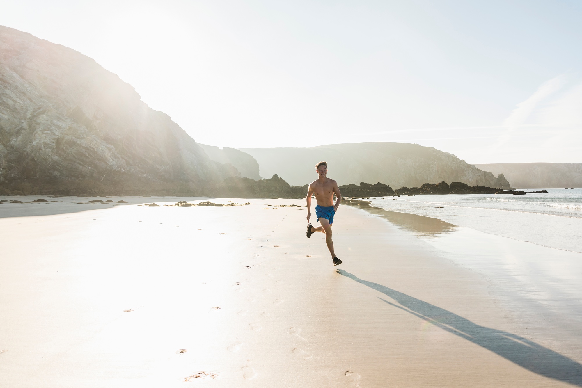 France, Crozon peninsula, young man running on the beach