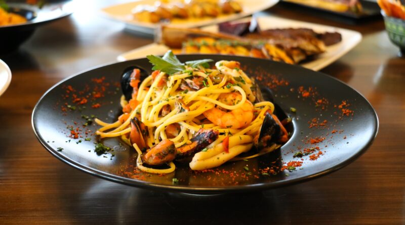 Healthy food concept. Spaghetti with shrimps, prawns and mussels. Blur plates with foods background.