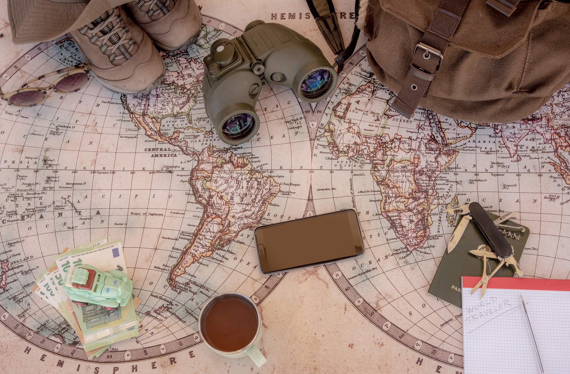 Old map to planning a world trip, travel, journey. Personal accessories on the table