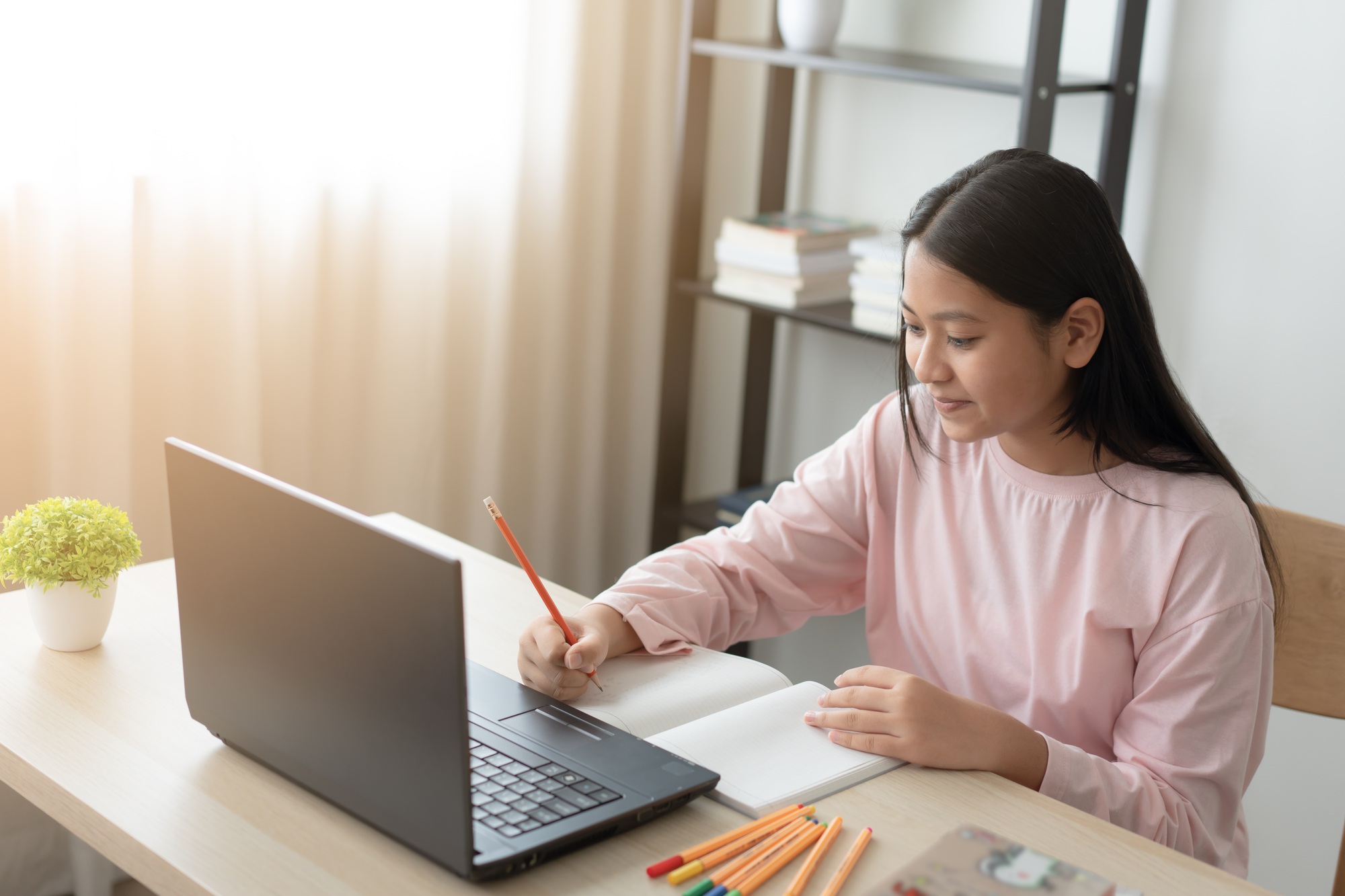 Asian school girl studying online class on laptop