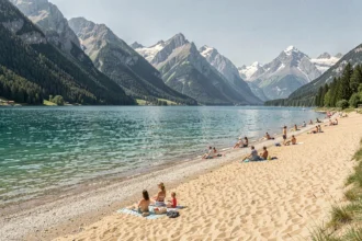 Vue panoramique d'une plage de lac de montagne en Auvergne-Rhône-Alpes avec eau turquoise et sommets alpins en arrière-plan
